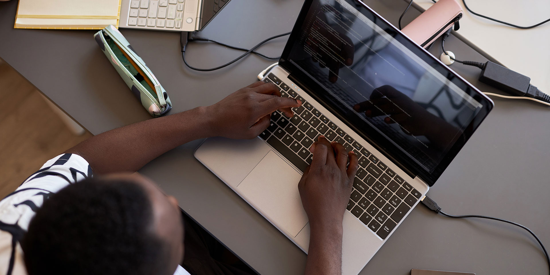 A student seen from above types on a laptop